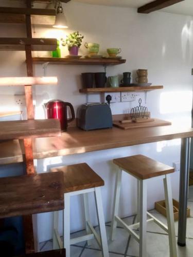 a kitchen with a counter and two stools in it at Historic school room in Helston