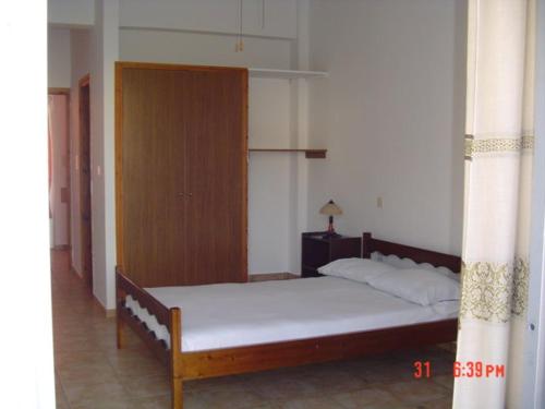 1 dormitorio con 1 cama y armario de madera en POSEIDON en Arkítsa