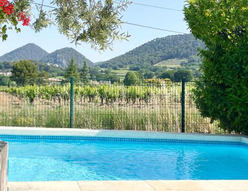 een zwembad met een hek en bergen op de achtergrond bij Entre vignes et horizon Appartement avec jacuzzi privatif et piscine commune chauffée in Sablet