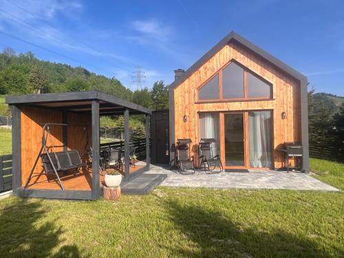 eine kleine Hütte mit einer abgeschirmten Veranda im Gras in der Unterkunft Tiny Domek w Dolinie Popradu, Piwniczna-Zdrój in Piwniczna-Zdrój