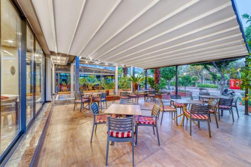 an outdoor patio with tables and chairs and windows at Kahya Hotel in Alanya