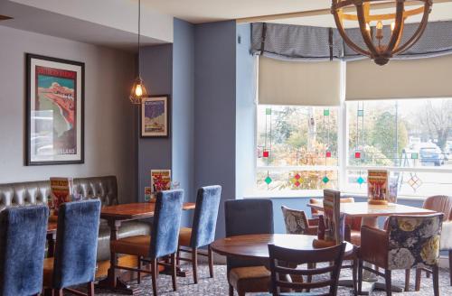 a dining room with tables and chairs and a window at Farmhouse Innlodge by Greene King Inns in Portsmouth
