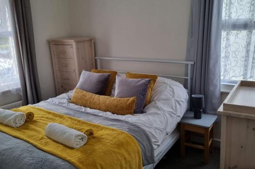 a bed with two pillows and a yellow blanket at Entire House With Garden & Parking Nr Ashford Int in Ashford