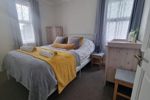 ein Schlafzimmer mit einem großen Bett und einer gelben Decke in der Unterkunft Entire House With Garden & Parking Nr Ashford Int in Ashford