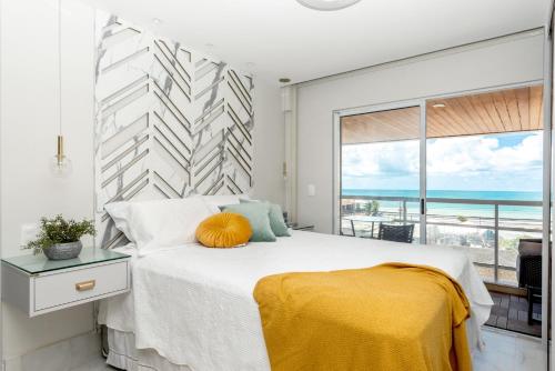 a bedroom with a large bed and a large window at DELUX PRAIA Flats in Natal