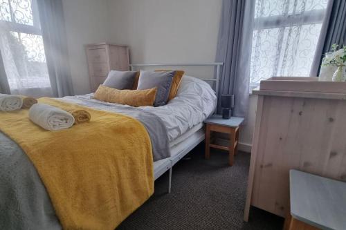 a bedroom with a bed with a yellow blanket and windows at Entire House With Garden & Parking Nr Ashford Int in Ashford