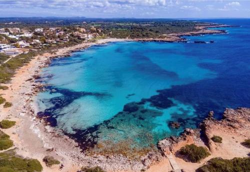 eine Luftansicht auf einen Strand mit blauem Wasser in der Unterkunft Casita Vista Mar Duplex - Son Xoriguer in Son Xoriguer