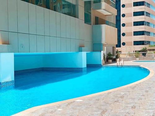 a large blue swimming pool next to a building at Two Continents Holiday Homes - Marvelous Marina Apartment in Dubai