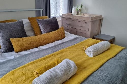 a large bed with two pillows and a yellow blanket at Entire House With Garden & Parking Nr Ashford Int in Ashford