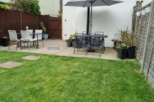 a patio with a table and chairs and an umbrella at Entire House With Garden & Parking Nr Ashford Int in Ashford