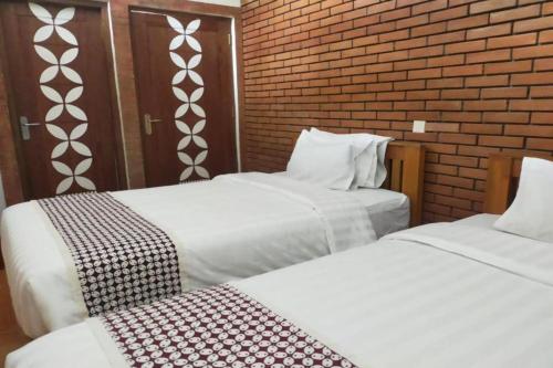 two beds in a room with a brick wall at Omah Rohadi Syariah by Ndalem Beong in Borobudur