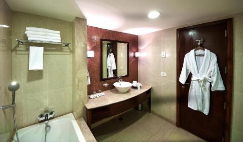 昌迪加爾的住宿－黃金廣場酒店，浴室配有盥洗盆和浴缸。