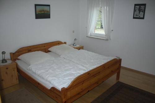 een houten bed in een slaapkamer met een raam bij Ferienwohnung Zum Schwalbennest in Eimke