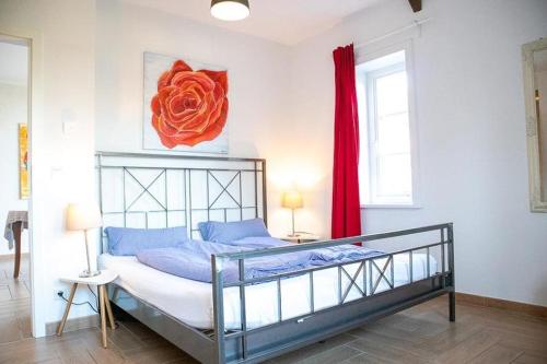 ein Schlafzimmer mit einem Bett mit einer roten Blume an der Wand in der Unterkunft Ahrentschildt's Ferienwohnung im Reetdachhaus 