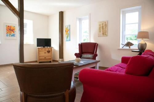 a living room with a red couch and chairs at Ahrentschildt's Ferienwohnung im Reetdachhaus in Eyendorf