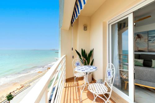 a balcony with a table and chairs and the beach at Genteel Home Victoria in Cádiz