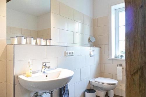 biała łazienka z umywalką i toaletą w obiekcie Ahrentschildt's Ferienwohnung im Reetdachhaus 