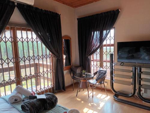 a living room with a tv and large windows at Majestic View Self Catering Guest House in Sabie