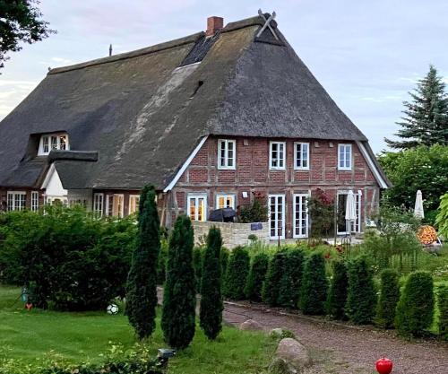 a large red brick house with a black roof at Ahrentschildt's Ferienwohnung im Reetdachhaus in Eyendorf