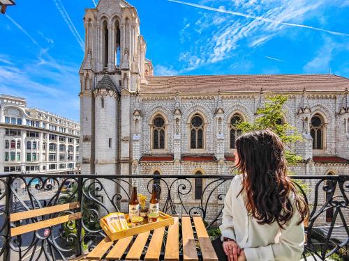 une femme assise à une table devant une église dans l'établissement Hôtel Du Centre, un hôtel AMMI, à Nice