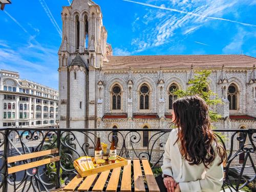 uma mulher sentada numa mesa em frente a uma igreja em Hôtel Du Centre, un hôtel AMMI em Nice