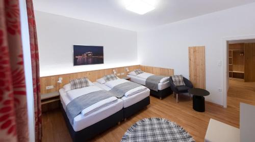 a bedroom with two beds and a table and a chair at Santner, Hotel in Eugendorf
