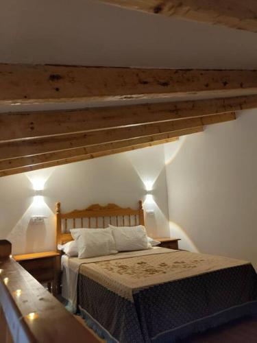a bedroom with a bed with two lamps and a wooden ceiling at La Cabañita in Tejeda