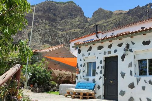 a white house with a blue door with mountains in the background at La Cabañita in Las Palmas de Gran Canaria