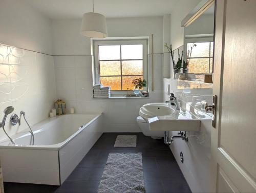 Baño blanco con bañera y lavamanos en Idyllisches Zuhause nahe Verden en Dörverden