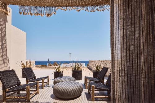 um grupo de cadeiras sentadas num pátio com praia em Serenity Suite Milos em Mandrakia