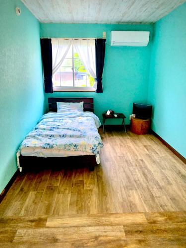 a bedroom with a bed with blue walls and a wooden floor at South Shore - Vacation STAY 89347 in Kannoura
