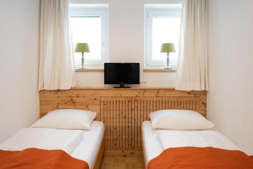 two beds in a room with two windows and a tv at Santner, Hotel in Eugendorf