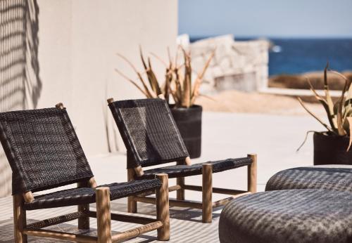 two chairs and a ottoman in front of plants at Serenity Suite Milos in Mandrakia
