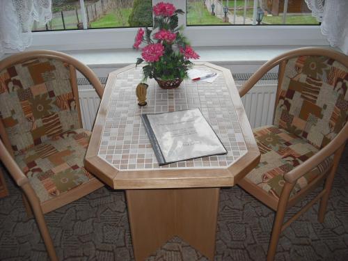 Una mesa con un jarrón de flores encima. en Pension Möhring, en Bad Suderode