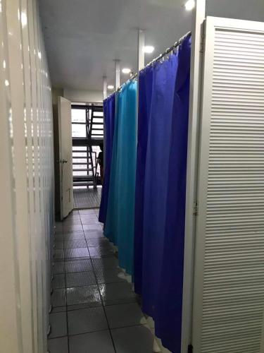 a row of blue shower stalls in a hallway at Burgos Hub Hostel in Manila