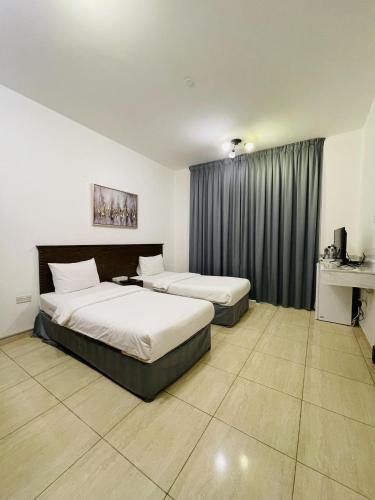 a hotel room with two beds and a window at Husin Al Khaleej Hotel Apartment in Seeb