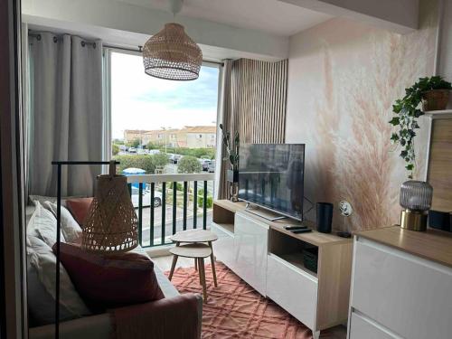 sala de estar con TV y balcón en Mon Appart à la plage, piscine, wifi, tv + Netflix, en Frontignan