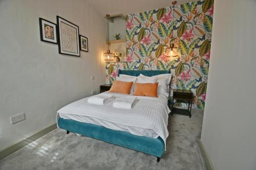 a bedroom with a blue bed with orange pillows at Quirky cottage set in Clitheroe in Clitheroe