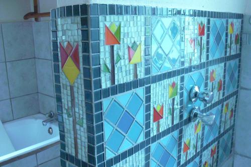 a bathroom with a shower with a blue tiled wall at Aspen Guest House in Clarens