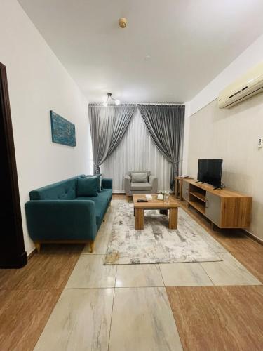 a living room with a blue couch and a table at Husin Al Khaleej Hotel Apartment in Seeb
