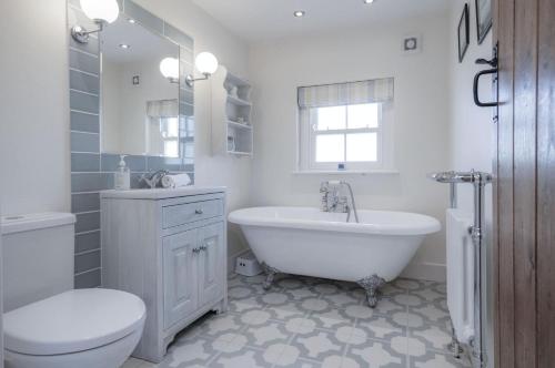 a white bathroom with a tub and a toilet and a sink at Dollars Cottage - 4 Bedroom Cottage - Llangennith in Llangennith