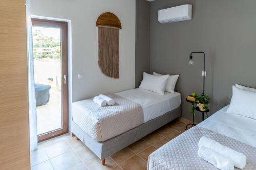 1 dormitorio con 2 camas y puerta a un balcón en Syra Suites, en Vári