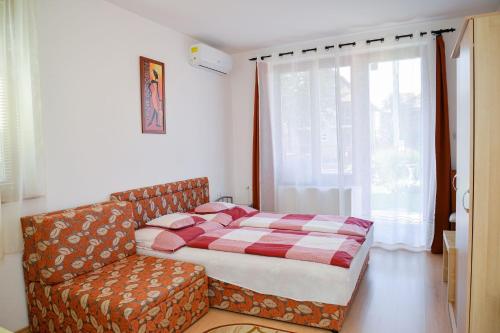 a bedroom with a bed and a couch and a window at SovaApartman in Hajdúszoboszló