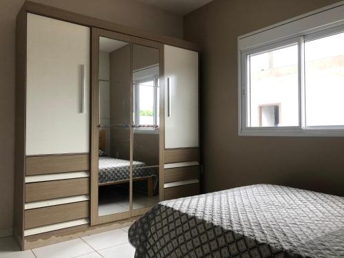 a bedroom with a mirrored cabinet and a bed at Casa praia de Itapirubá a 100 metros do mar in Imbituba