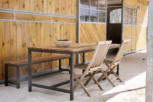 una mesa de madera con 2 sillas y un bol en la parte superior en Charming holiday apartment on a rural farm outside Laholm, en Laholm