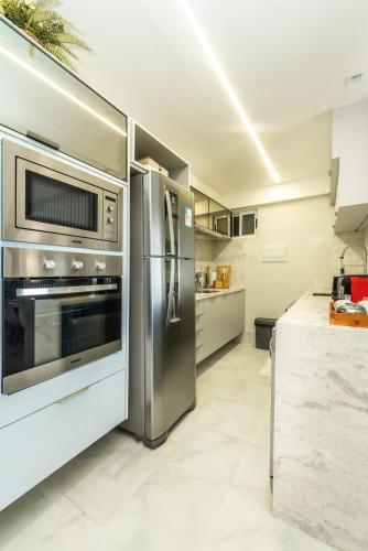 a kitchen with a stainless steel refrigerator and a microwave at DELUX PRAIA Flats in Natal