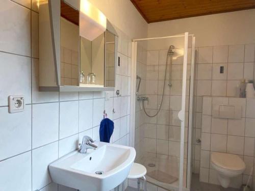 y baño blanco con lavabo y ducha. en Ferienwohnung Bädke en Müden