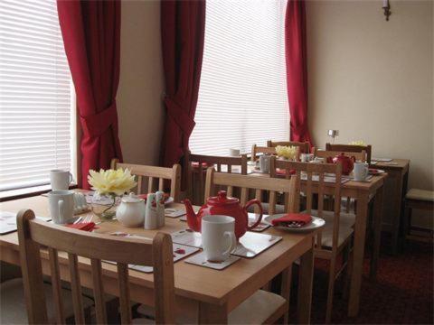 a dining room table with red drapes and a table and chairs at Park House Rooms in Lochinver