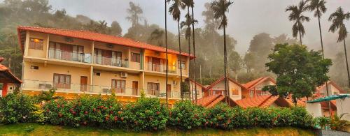 a row of buildings with palm trees in the background at Hill Crest Resort - Coorg in Madikeri