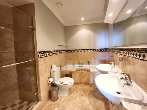a bathroom with a toilet and a sink and a tub at 603 Oyster Rock Umhlanga Rocks in Durban